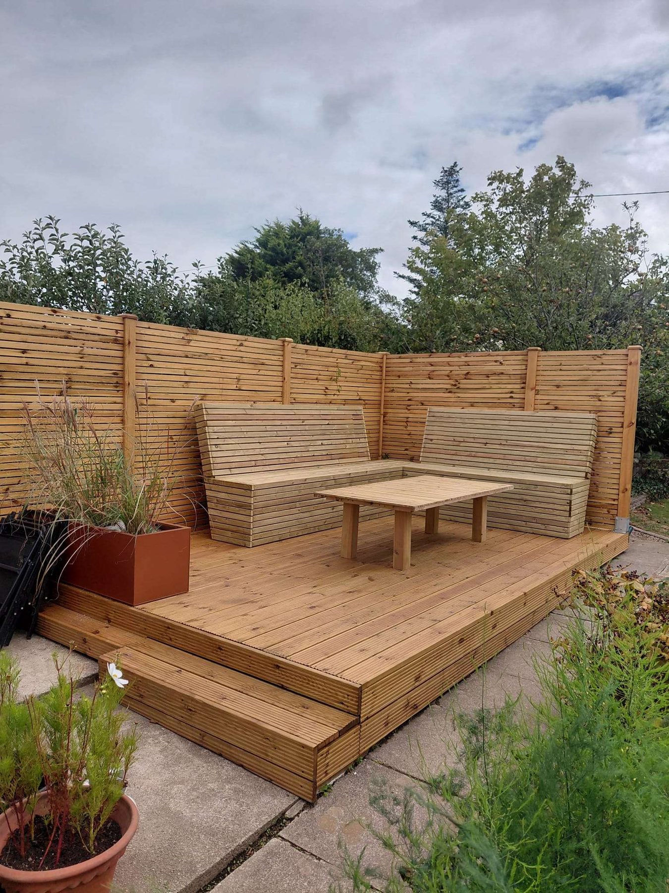 Timber deck with built-in bench seating and a slatted table, built by Benno